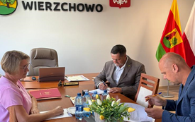 Zdjęcie przedstawia oficjalne spotkanie w urzędzie gminy, o czym świadczy umieszczone na ścianie godło Polski oraz napis &bdquo;Gmina Wierzchowo"